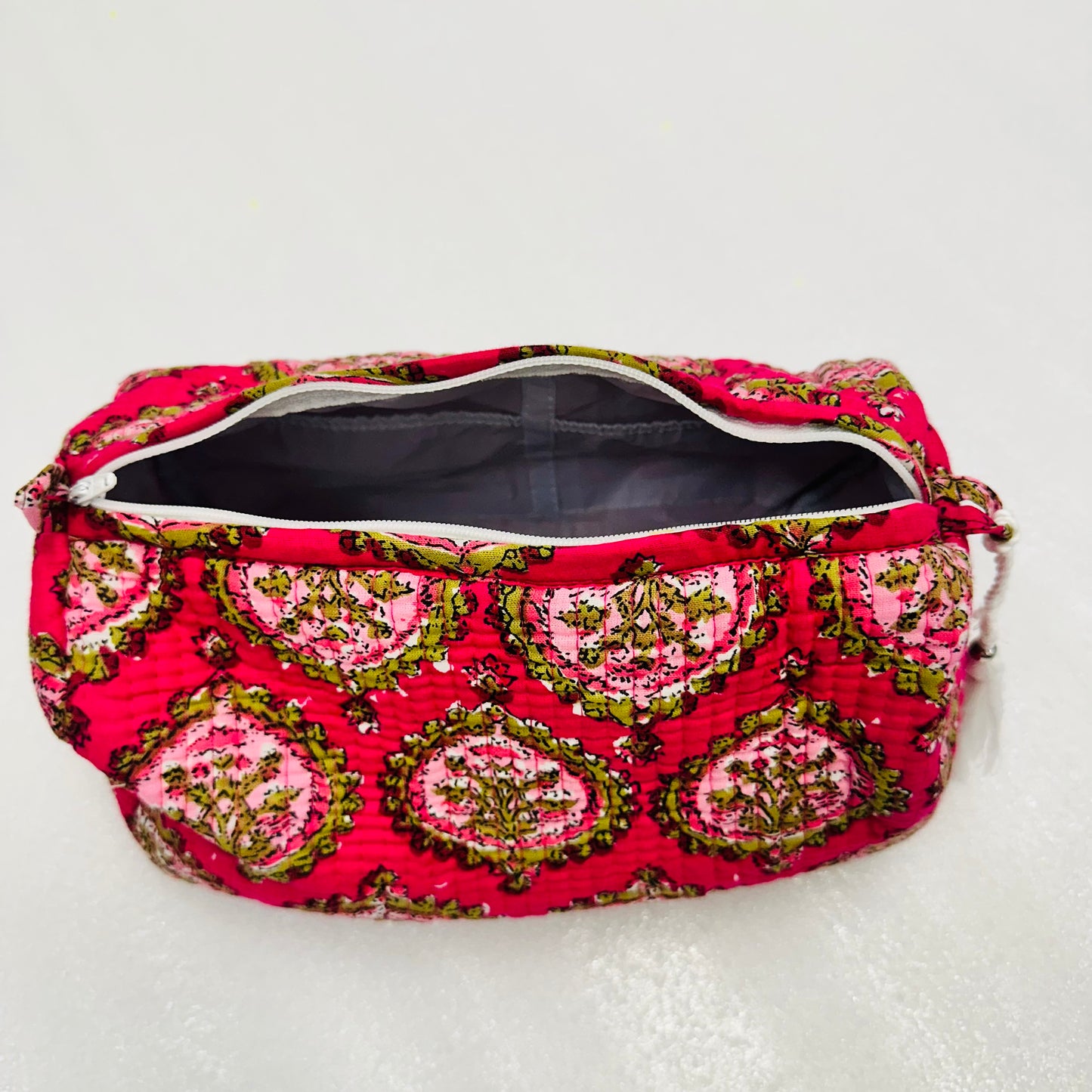 Pink and green patterned pouch on a white background