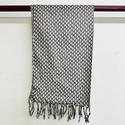 Black and white patterned scarf with fringes on a wooden rod against a white background